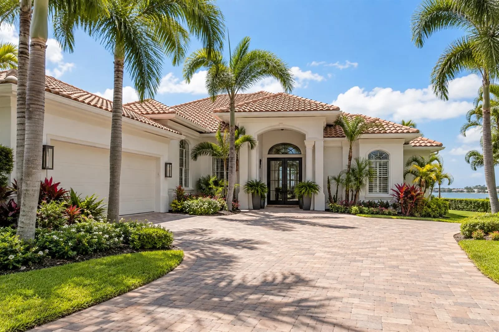 Single-family home with a tile roof, a two-car garage and a paver driveway